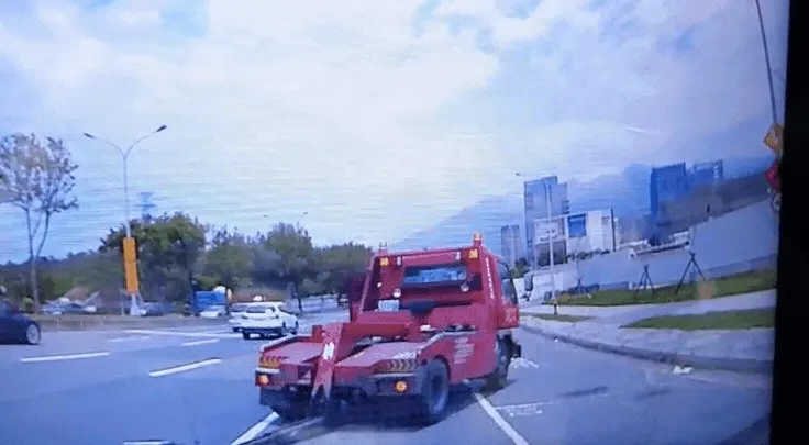 拖吊車人員身手俐落又跳回沒關門的車上，看似順利煞停拖吊車在路邊。讀者提供