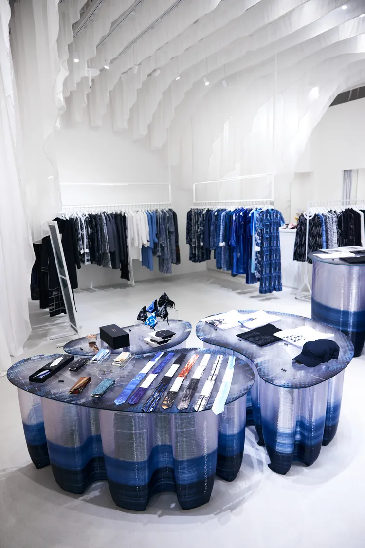 天花板懸掛的防焰布幔與採用3D列印手法製成的透明藍色展示桌，在光影交織下增添了視覺的變化性。品牌提供