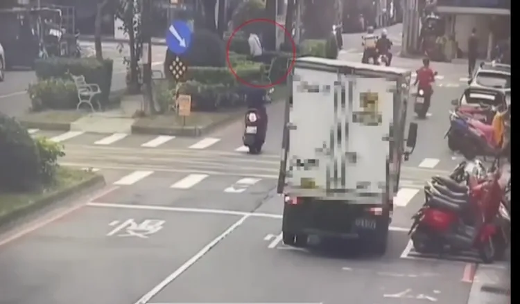 路邊監視器拍到張男(紅圈處)提著骨灰罈，走上分隔島棄置。翻攝畫面