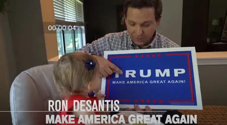 佛州州長迪尚特（右）曾在5年前的競選影片中，秀出川普的競選標語「讓美國再度偉大」給女兒看。翻攝Youtube/ Ron DeSantis Campaign 