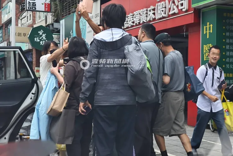 一群男粉絲包圍著豆花妹，要求簽名、合照。特勤中心攝