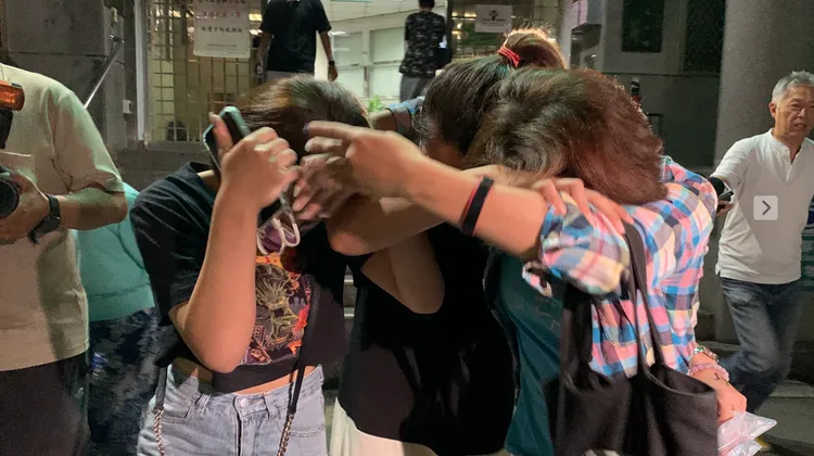 幼保員何女(中)由2名親友協助避開媒體鏡頭。丁牧群攝