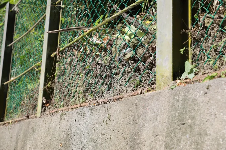 針對東勢街26巷旁邊坡落石問題，市府表示會先將擋土牆上的護欄圍網妥善修復。翻攝照片