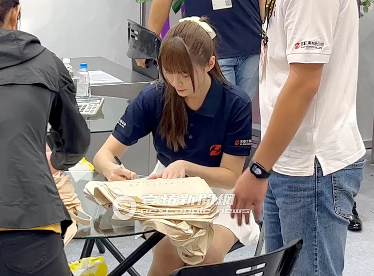 啦啦隊女神短今（中），耐心在數個帆布袋上簽名，準備發給粉絲。特勤中心攝