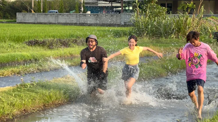 阿翔（右）、籃籃、製作人在黑泥田裡狂奔。民視提供