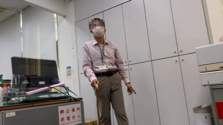 葉男杵著枴杖從辦公室走到門外受訪。鮮明攝