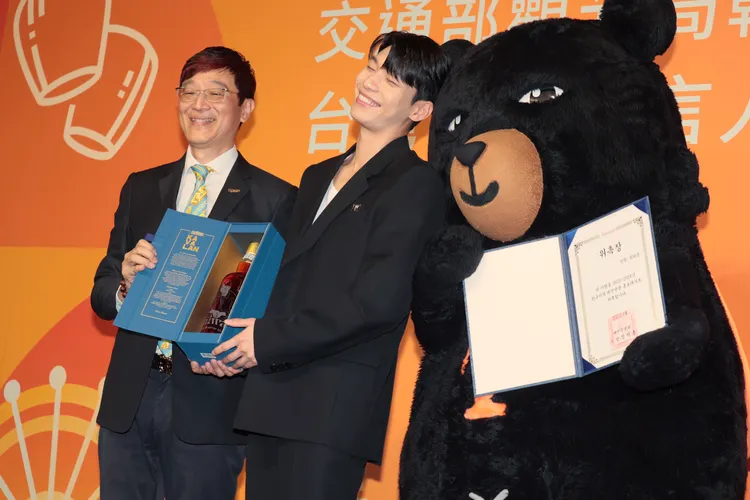 魏嘏雋（中）喜收觀光局贈送刻有他肖像的葛瑪蘭威士忌，開心到靠在喔熊頭上。彭欣偉攝