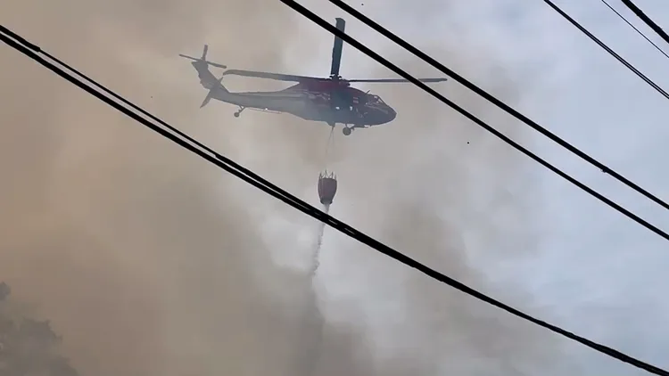 空勤直升機在火煙上空執行空中灑水任務。民眾提供