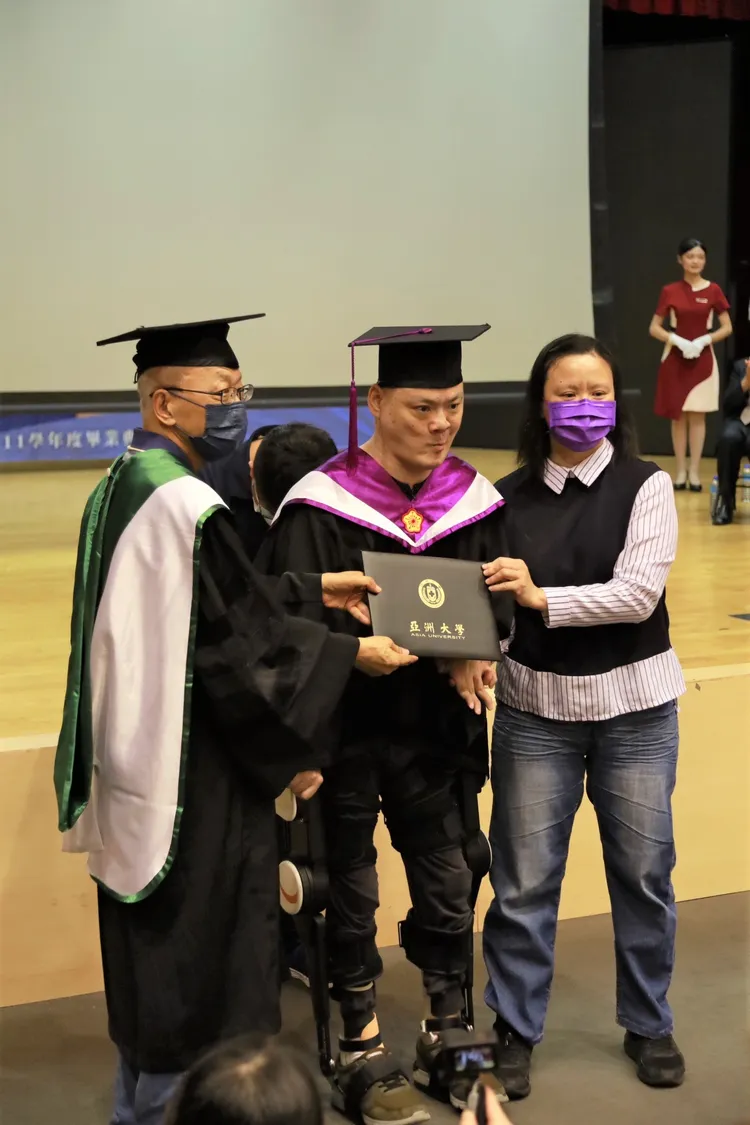 陳銘哲穿著「外骨骼機器人」人生第1次從輪椅站起來，由大姊陳秀玉(右)陪同領獎。亞大提供