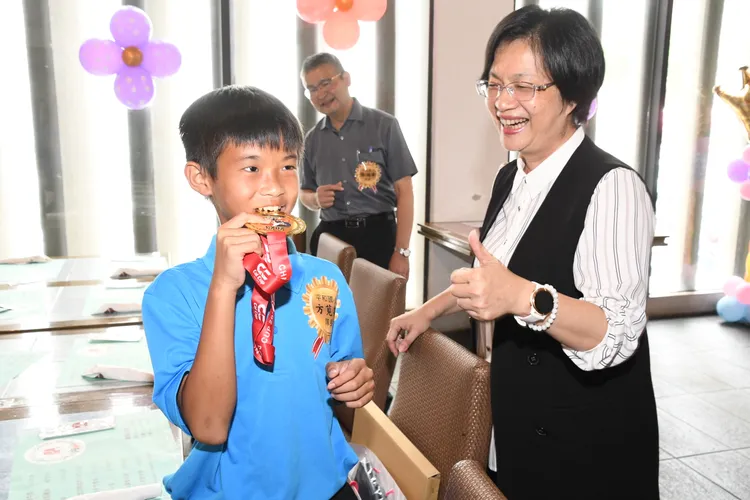 小選手開心地咬著金牌，與王惠美合影留念。縣府提供