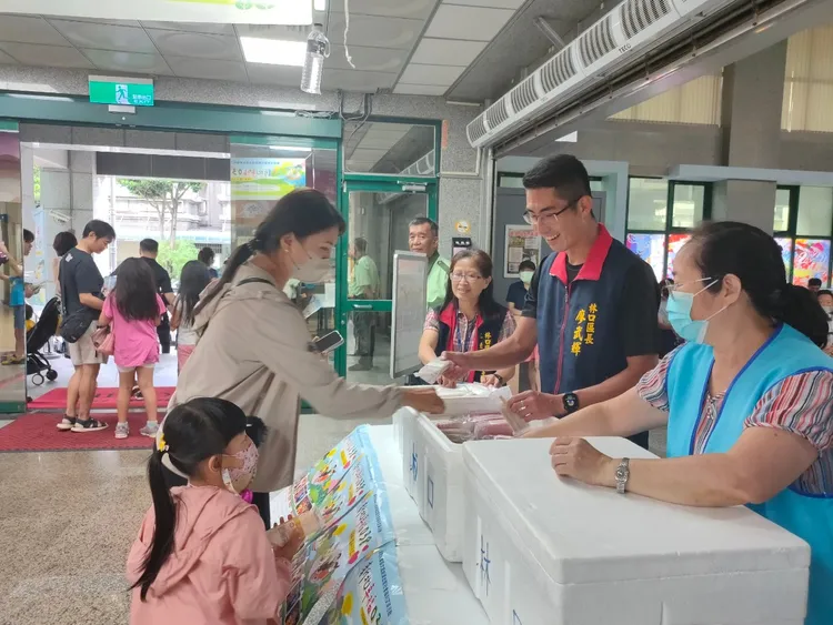林口區長廖武輝與現場大朋友小朋友分享暑聖品台電冰棒。公所提供