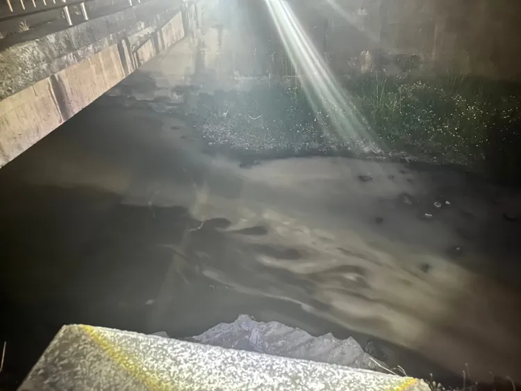番仔園圳被亂倒強酸廢油，出現一片奶茶色。警方提供