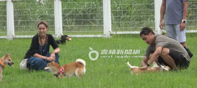 在狗公園裡，鄭楠鐘（右）和女友都蹲下身段，摸著狗狗玩耍。特勤中心攝