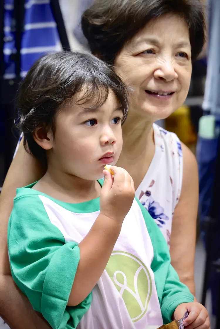 Dylan（左）向外婆討零食，邊吃邊看媽媽受訪。林林攝
