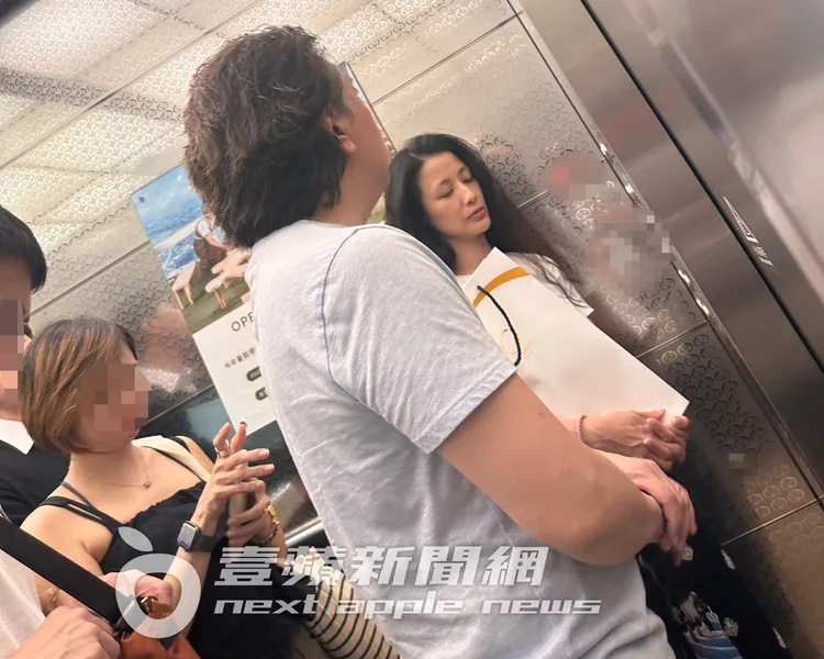 李蒨蓉（右）素顏抱著日本清酒，和老公李德立從B3停車場搭電梯上樓。讀者提供