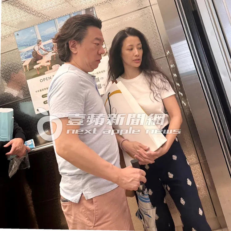 素顏的李蒨蓉（右）抱著清酒，跟老公在台北101搭電梯，讀者形容「還是很漂亮」。讀者提供