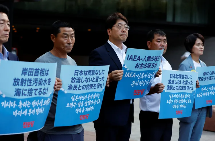 場外有韓國民眾舉牌抗議。路透社