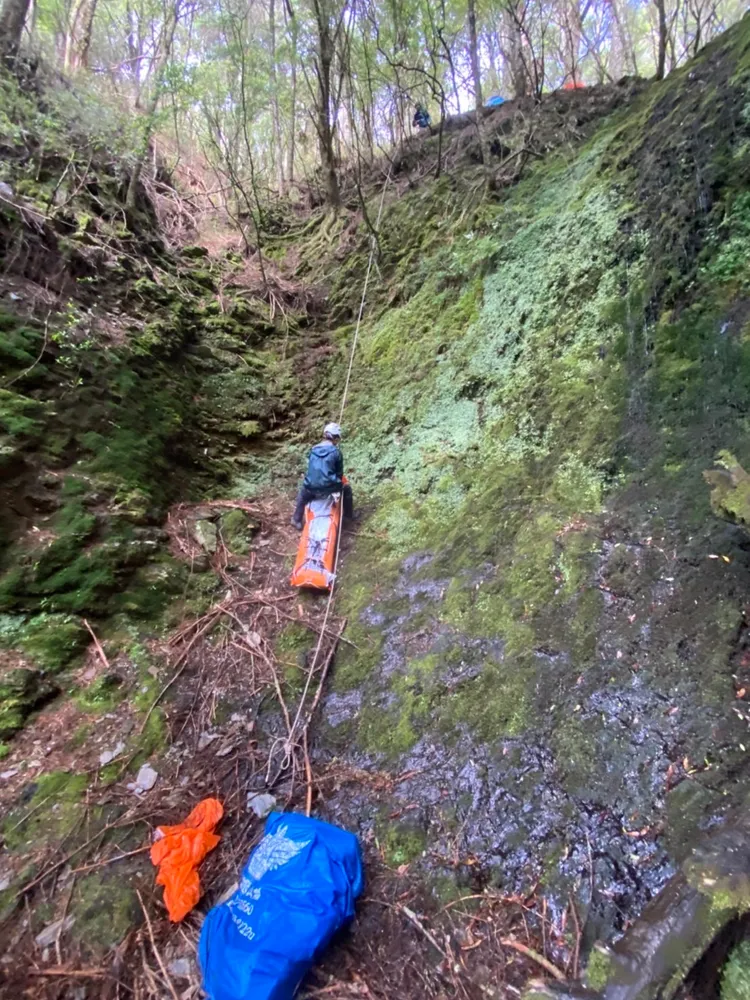 搜救人員將遺體打包，以繩索拖拉到步道。南投縣消防局提供