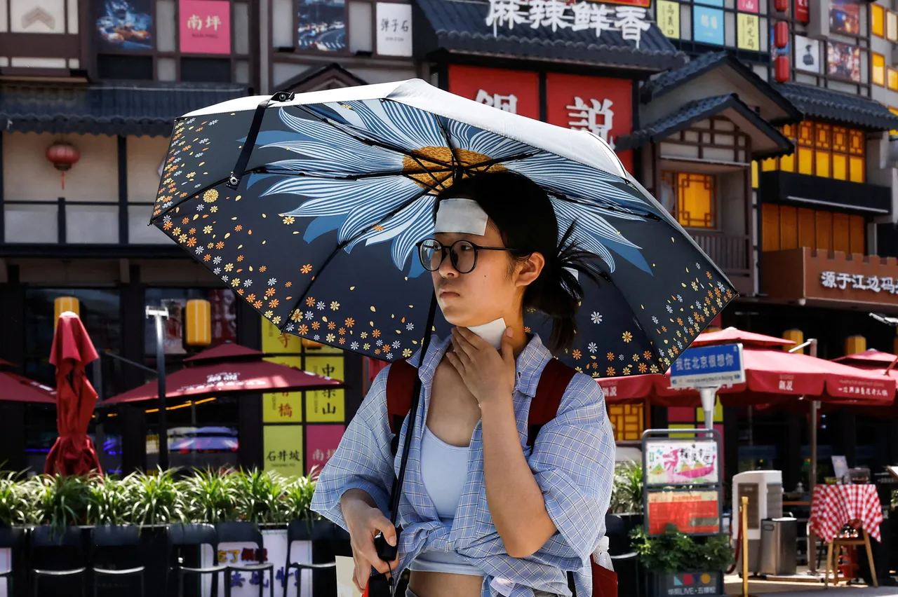 中國北京市近日頻頻高溫,一名女子6月23日撐傘上街,額頭還貼了冰涼貼降溫。路透社