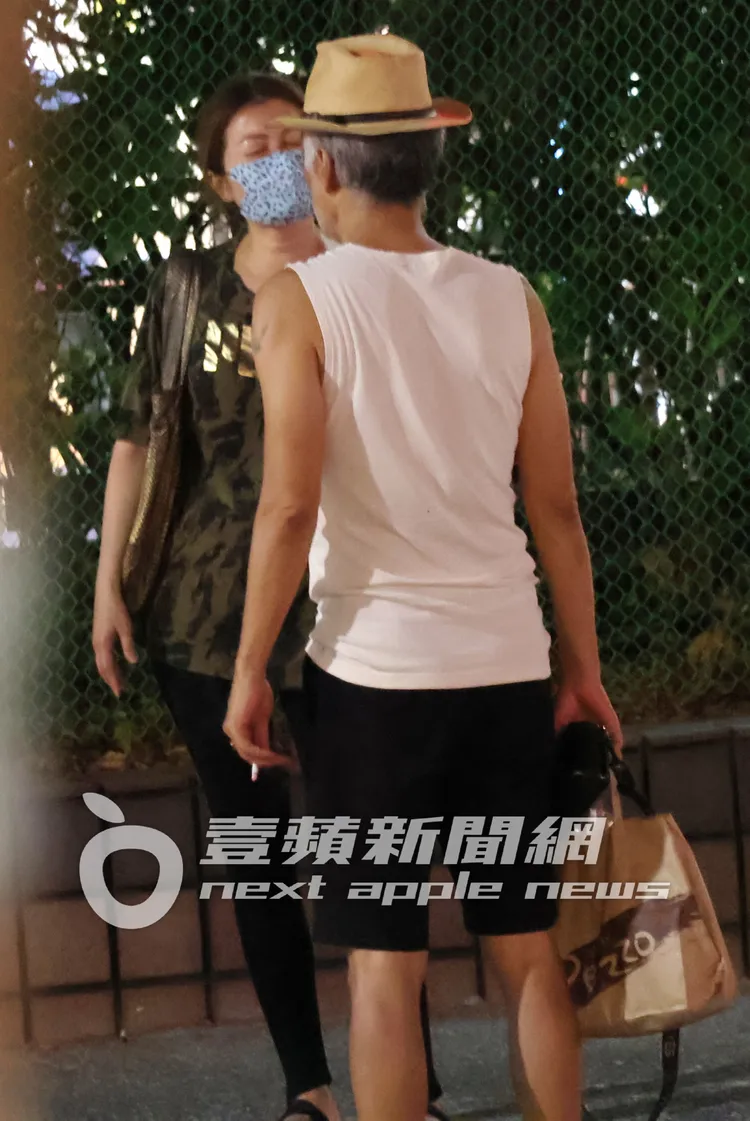 周禹侯（右）手拿著麵包袋及香菸，與輕熟女在路邊面對面緊靠在一起。特勤中心攝