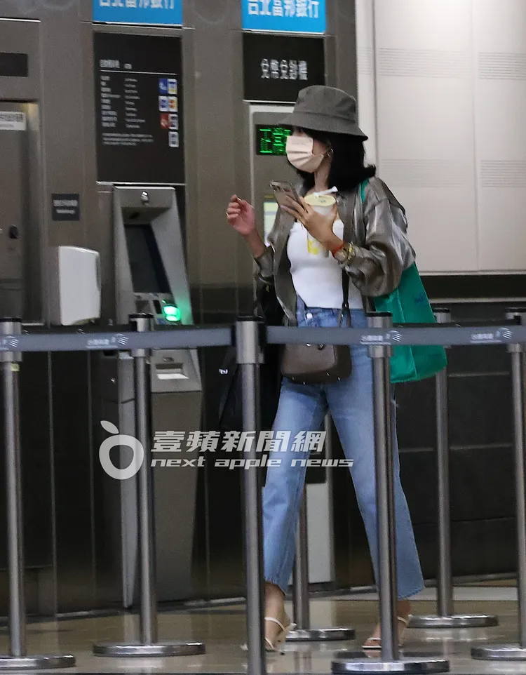 內內單手拿著手機及手搖飲走去售票機。特勤中心攝