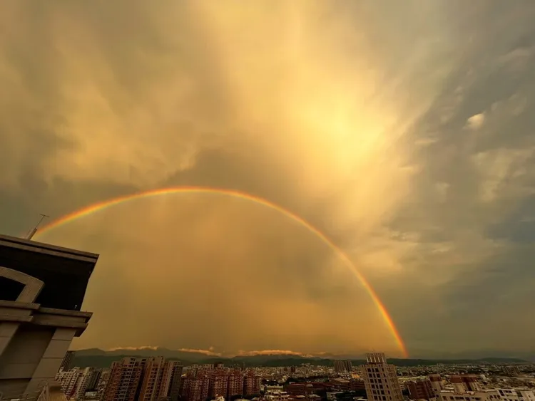 台中市區11日傍晚降下大雨，雨勢趨緩後，民眾抬頭便可見彩虹橫跨台中市區，因降雨後能見度佳，甚至能見到遠處的玉山與彩虹一同出現。（翁清雅提供）中央社