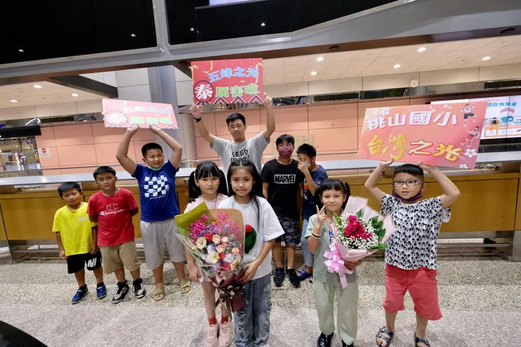 拿著鮮花等著兄弟姊妹歸國的小朋友，心中充滿著興奮與期待。陳志淵攝