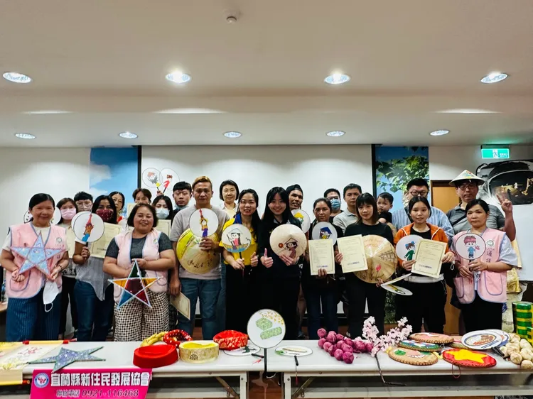 全體新住民學員手持完成扇子彩繪作品一起與阮如庄及服務站同仁合影。翻攝畫面