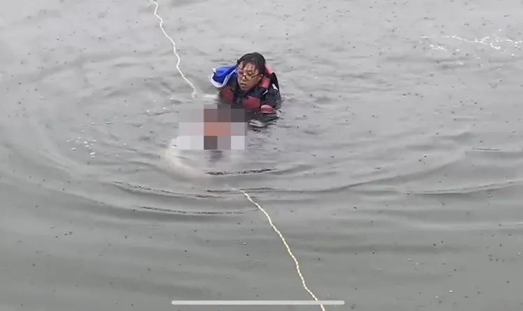 男子脫困游出車外，由海巡人員拖帶至岸上。翻攝畫面