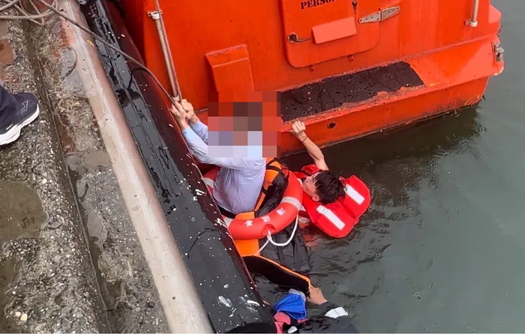 男子脫困游出車外，由海巡人員拖帶至岸上。翻攝畫面