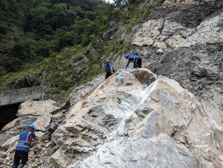 工班涉險爬上巨石進行裂解，隨時注意邊坡有無落石。公路總局提供