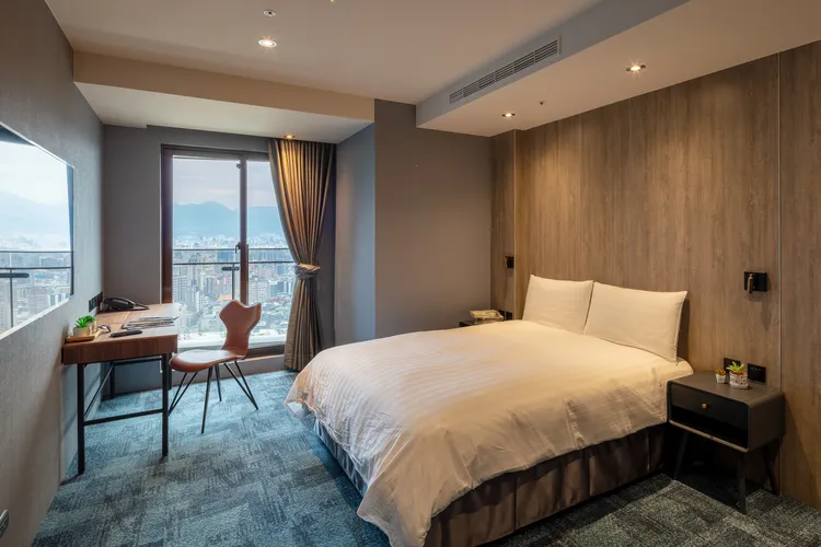 尊爵雙人房大片落地窗享絕佳視角，暑假浮動房價一晚約5500元起，使用大稻埕煙火方案連住兩晚，一晚僅4300元起。小鹿文娛提供