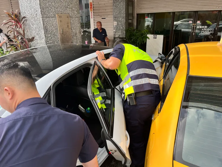 白色奧迪撞上路邊停車的計程車，2車再一同塞進騎樓。讀者提供