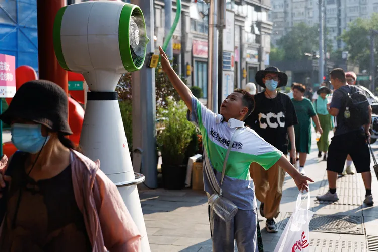 男童7月19日在北京街頭伸長手感受風扇涼風。路透社