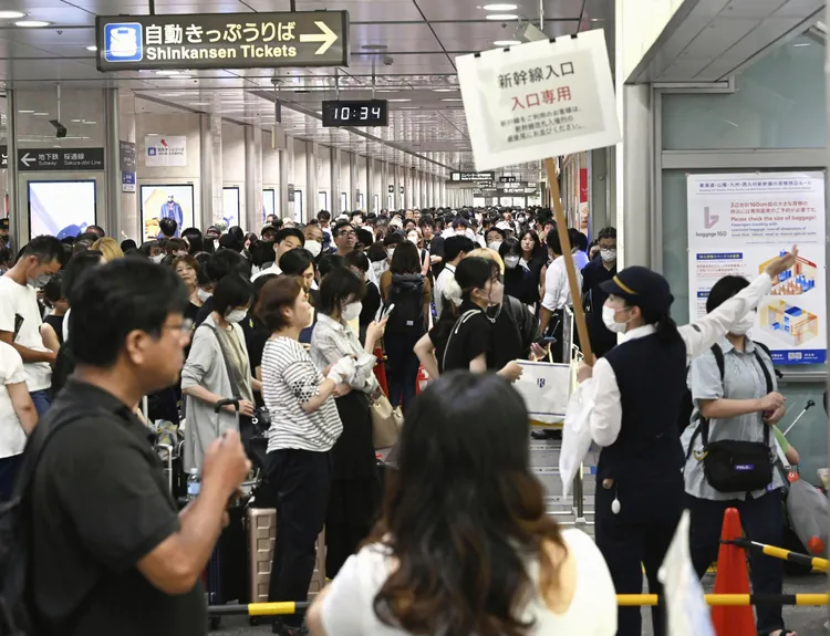 新幹線名古屋站的工作人員16日舉牌引導旅客。美聯社