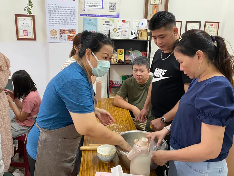 講師劉語喬(左一)向越南新住民玉蓮(右一)傳授醒麵的技巧。移民署提供