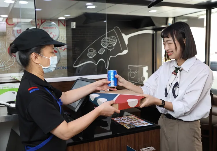 外帶客家披薩用客語說「來食飯」，即贈送罐裝可樂一瓶。達美樂提供