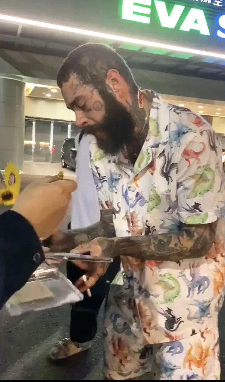 美國嘻哈巨星Post Malone仔細簽著自己的CD專輯。讀者提供