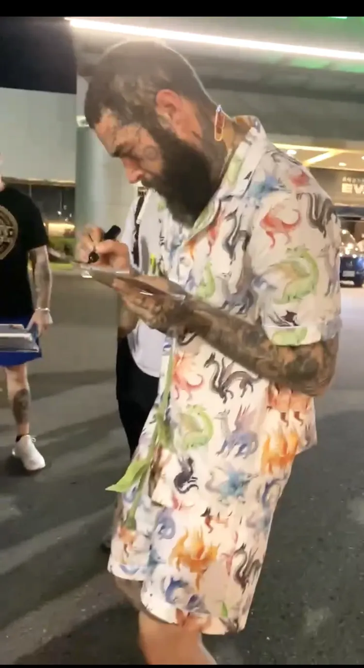 美國饒舌巨星馬龍Post Malone，在松山機場外拿起唱片仔細簽名。讀者提供
