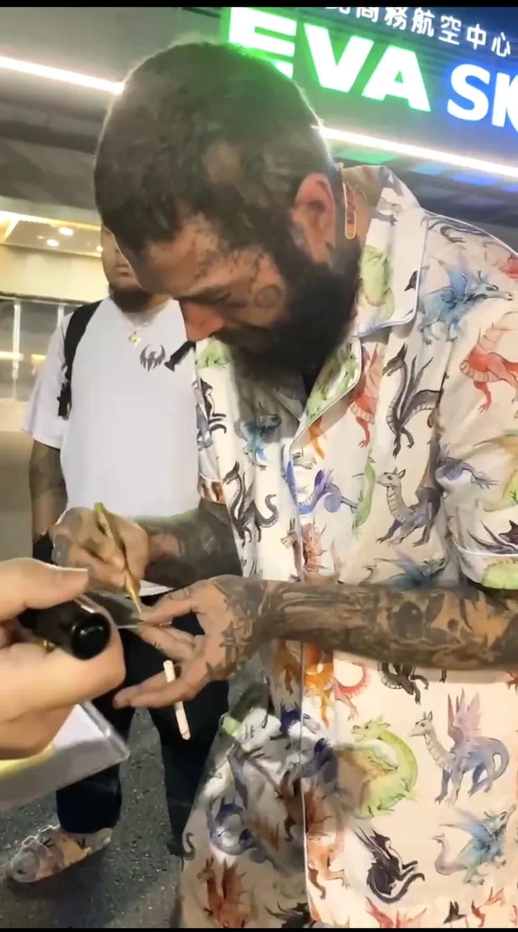 美國饒舌巨星馬龍，叼香菸零距離寵粉簽名。讀者提供