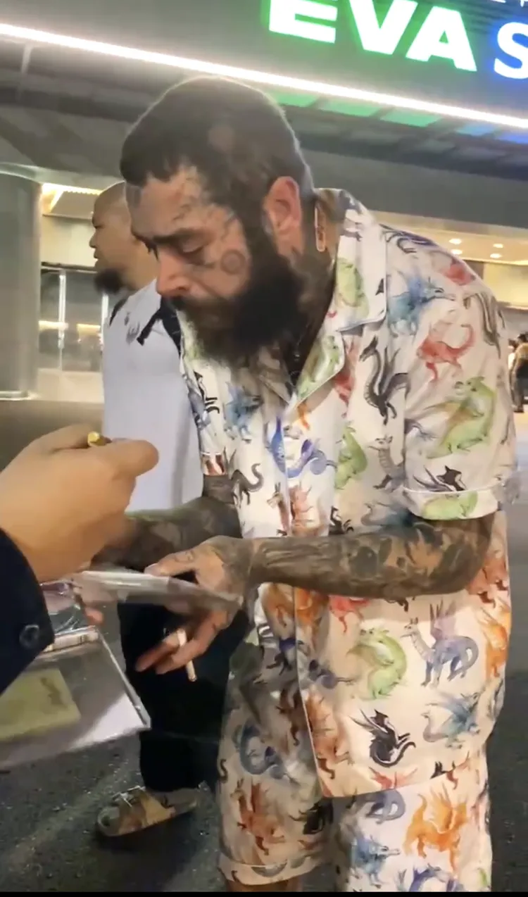 美國饒舌巨星馬龍叼著菸認真幫粉絲簽名唱片。讀者提供