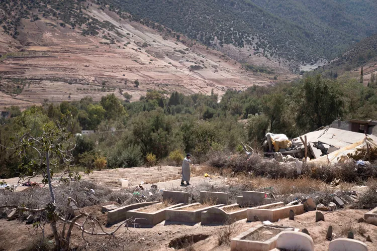 災區一名男子佇立在墓園中，身邊全是地震死者的新墳。美聯社