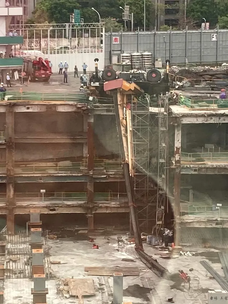 工地吊車翻覆且吊臂懸掛外牆，讓人看了怵目驚心。翻攝畫面