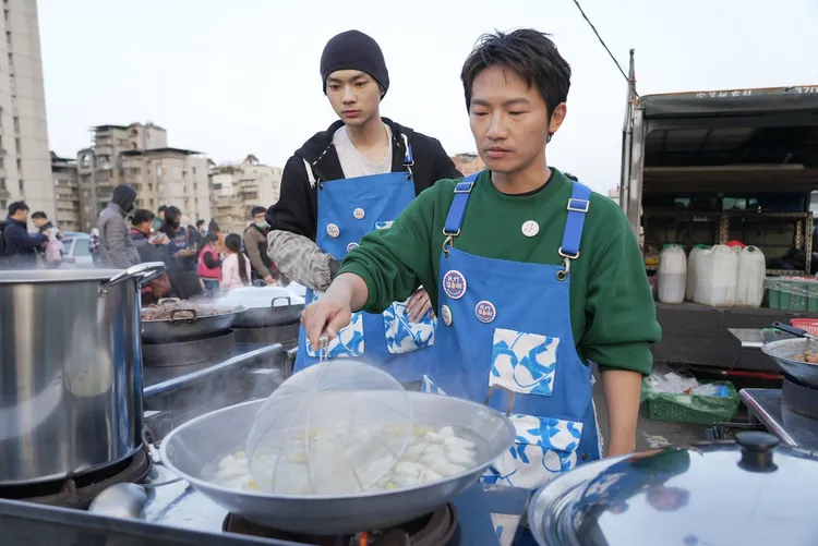 蔡昌憲（右）夜市現場煮起自家水餃，安撫排隊已久的民眾。華視提供