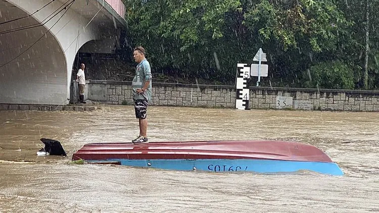 大叔淡定地站在翻覆的小船上隨著水流前行。翻攝自「大埔人大埔谷」臉書