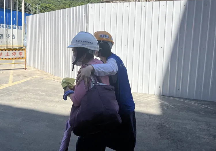 民眾取物後身體不適，由工作人員陪同到一旁休憩。北市都發局提供