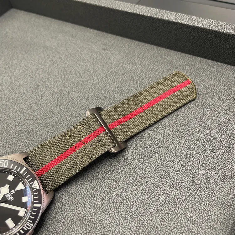 錶帶則為中央紅色條紋的軍綠色一體式織紋設計。張家玲攝