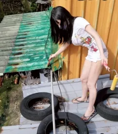 彭小姐爬上梯子幫屋主刷鐵皮屋頂油漆。取自爆廢公社二館