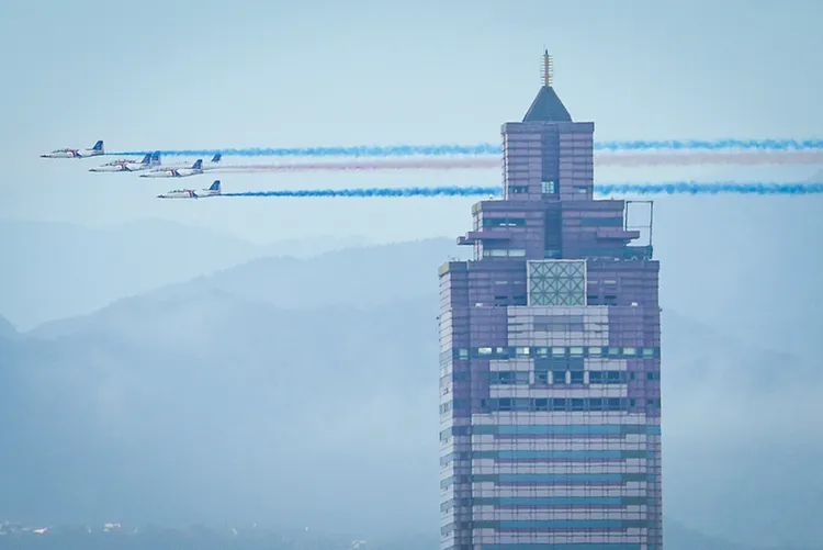 國軍28日展開空中全兵力預演，6架AT-3 教練機施放彩煙飛過台北車站站前新光三越上空。 中央社