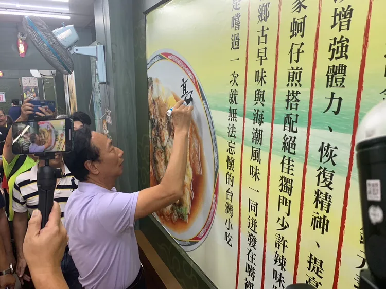 郭台銘應商家要求，在牆上簽名留念。記者葉先鵬攝